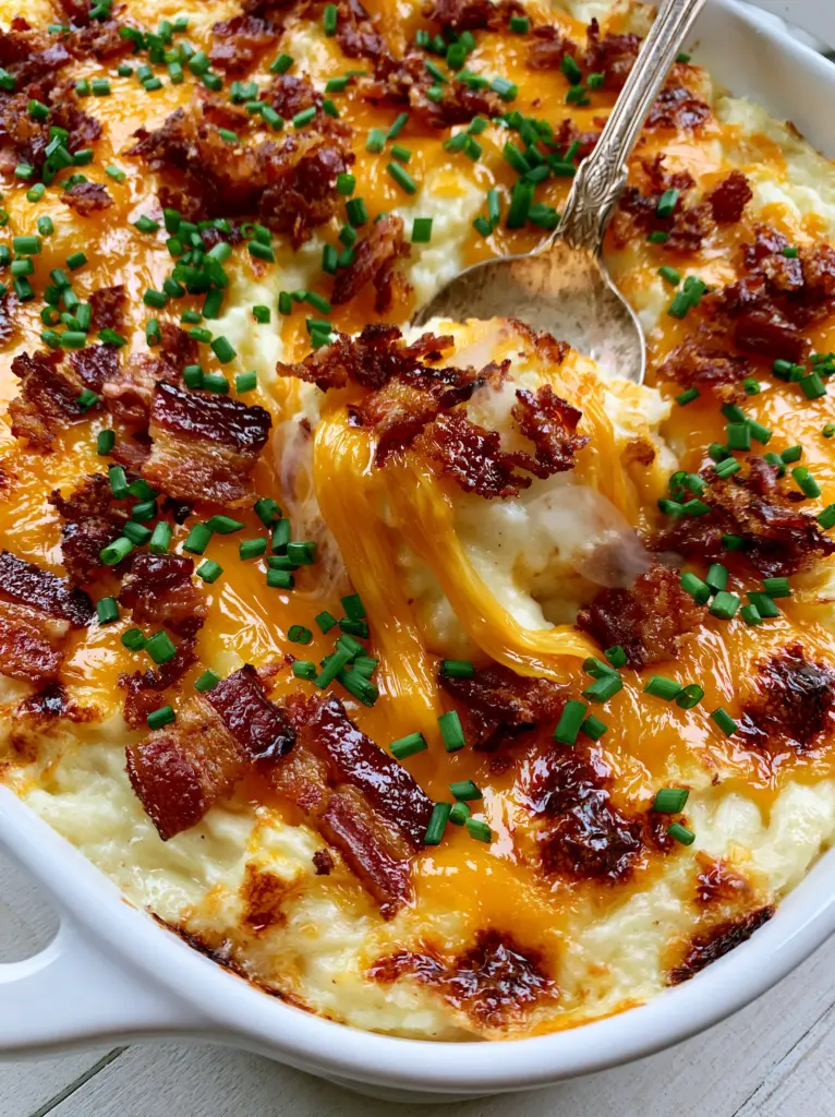 A vintage spoon lifting a scoop of creamy twice baked potato casserole with steam rising and thick cheese pulls.