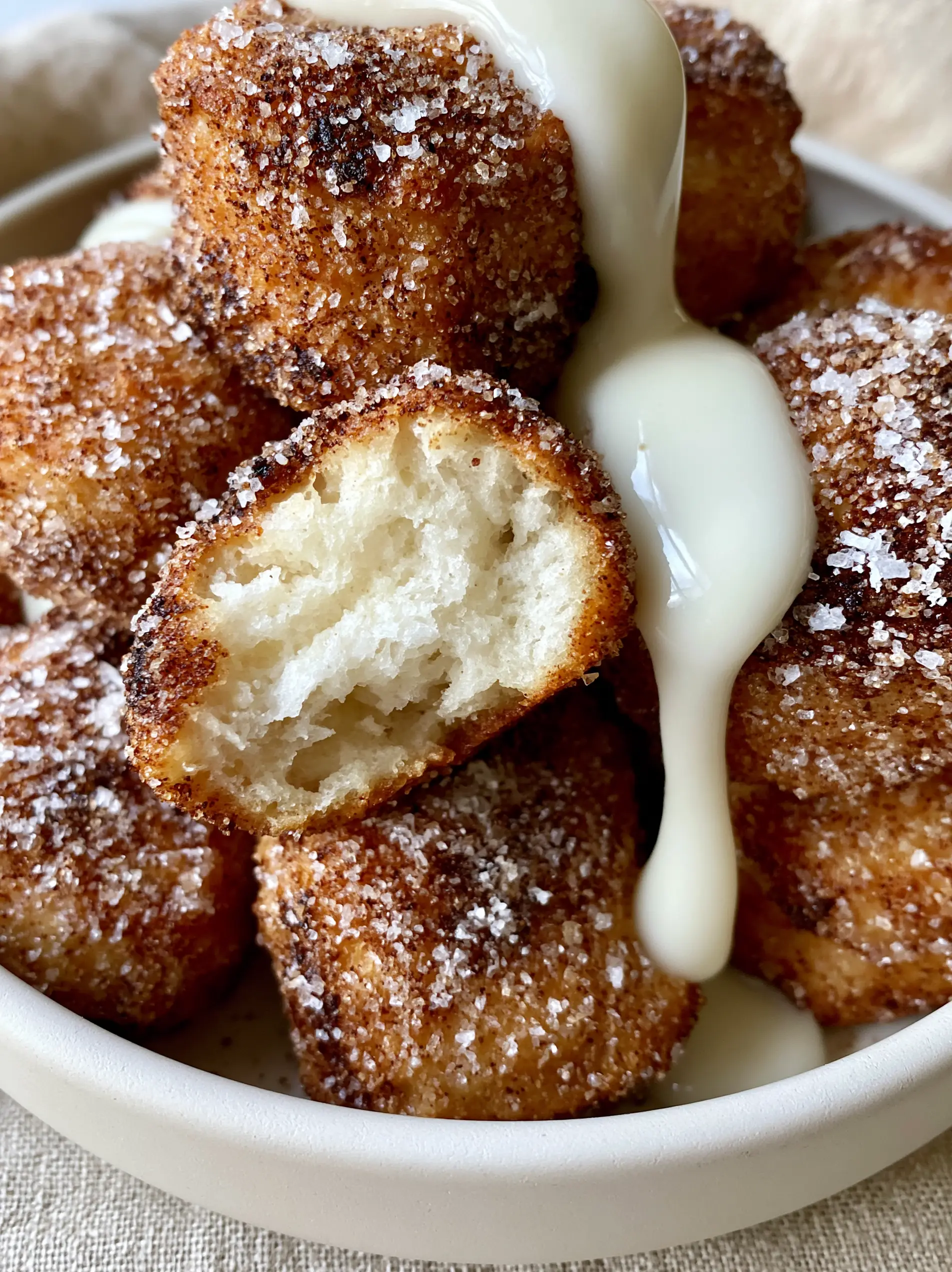 Close-up of a torn cinnamon sugar biscuit bite revealing a steaming, soft white pillowy dough interior.