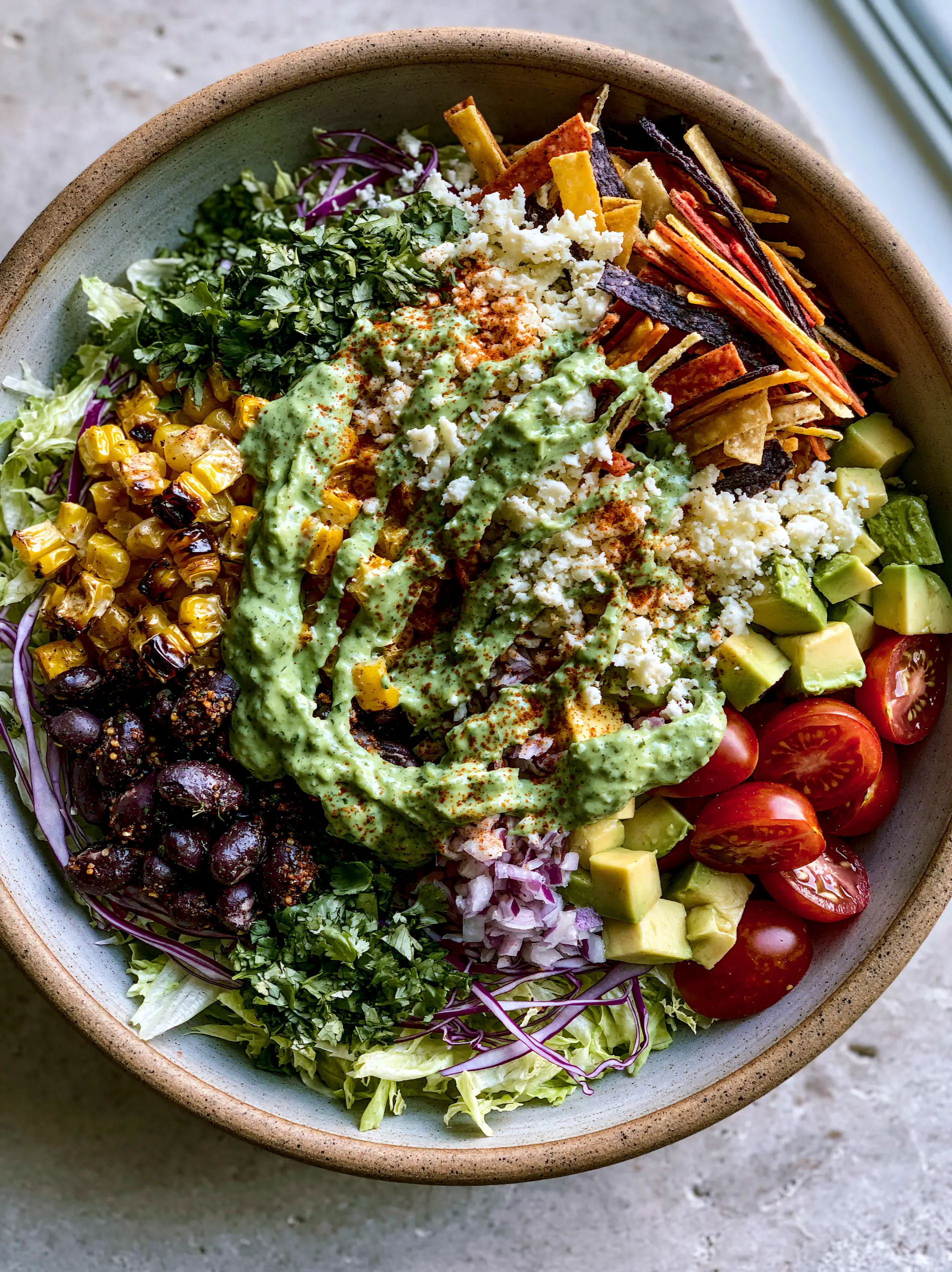 A large rustic ceramic bowl filled with Mexican chopped salad, featuring finely shredded romaine and purple cabbage. (Mexican chopped salad)