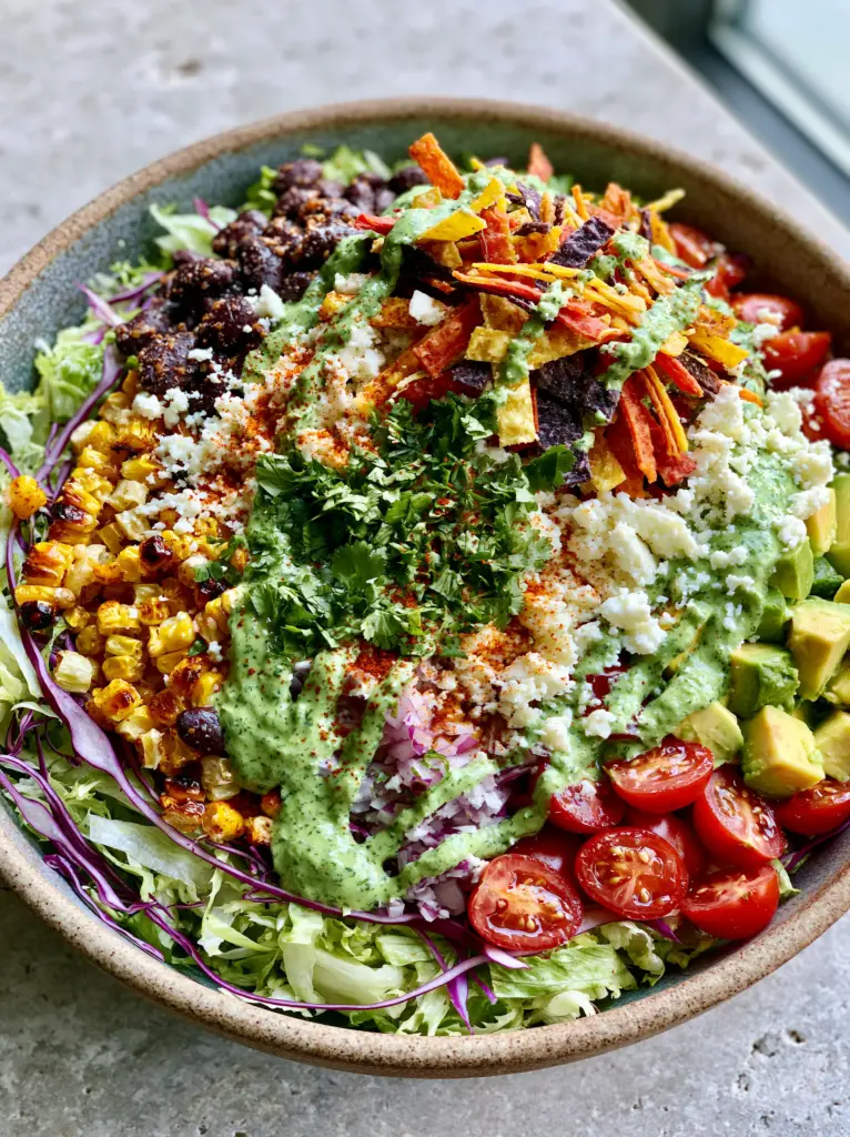 Artistic drizzle of green cilantro lime crema over a colorful Mexican chopped salad.