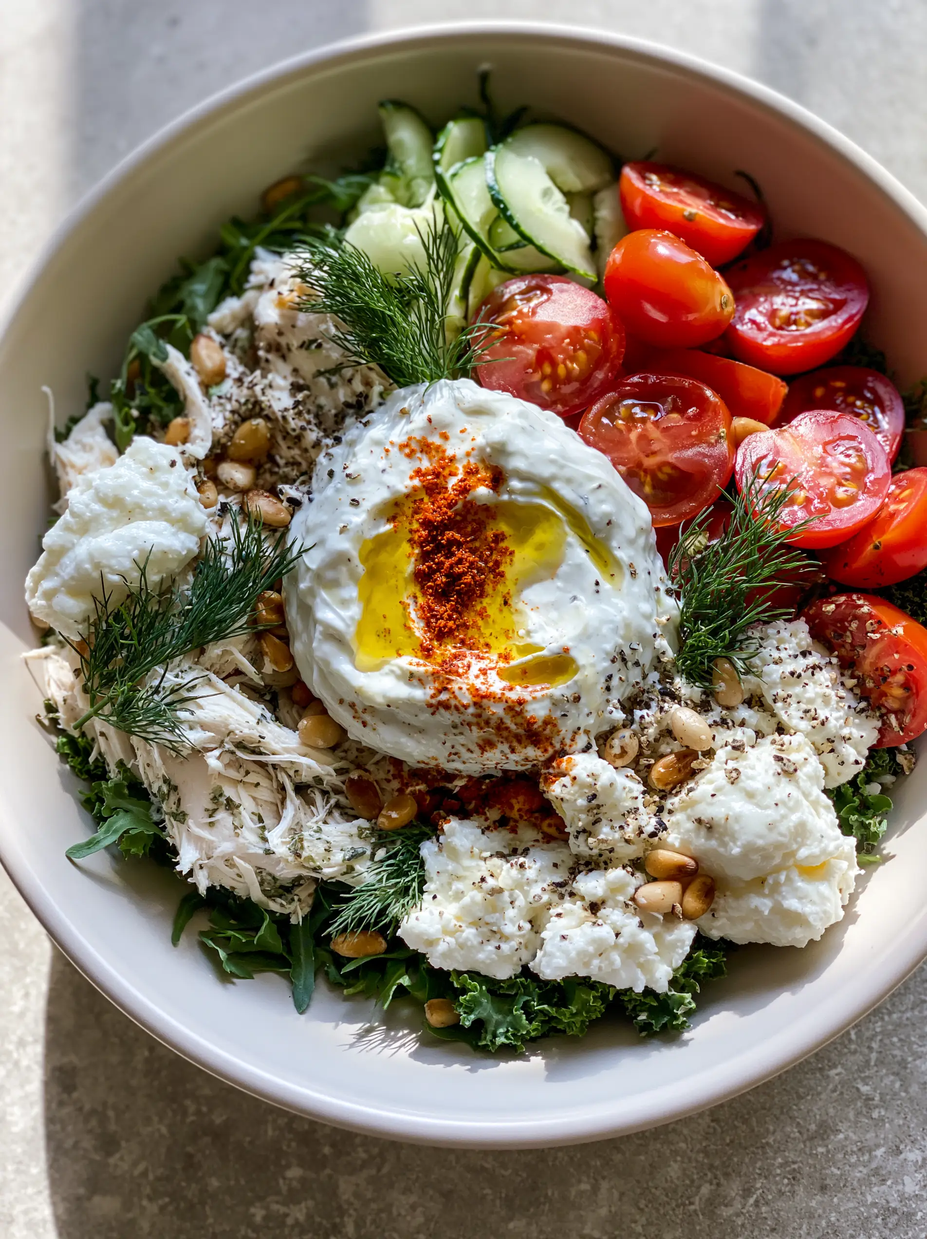 Overhead view of a Mediterranean bowl featuring chilled shredded chicken and dark leafy greens. (healthy summer dinners)