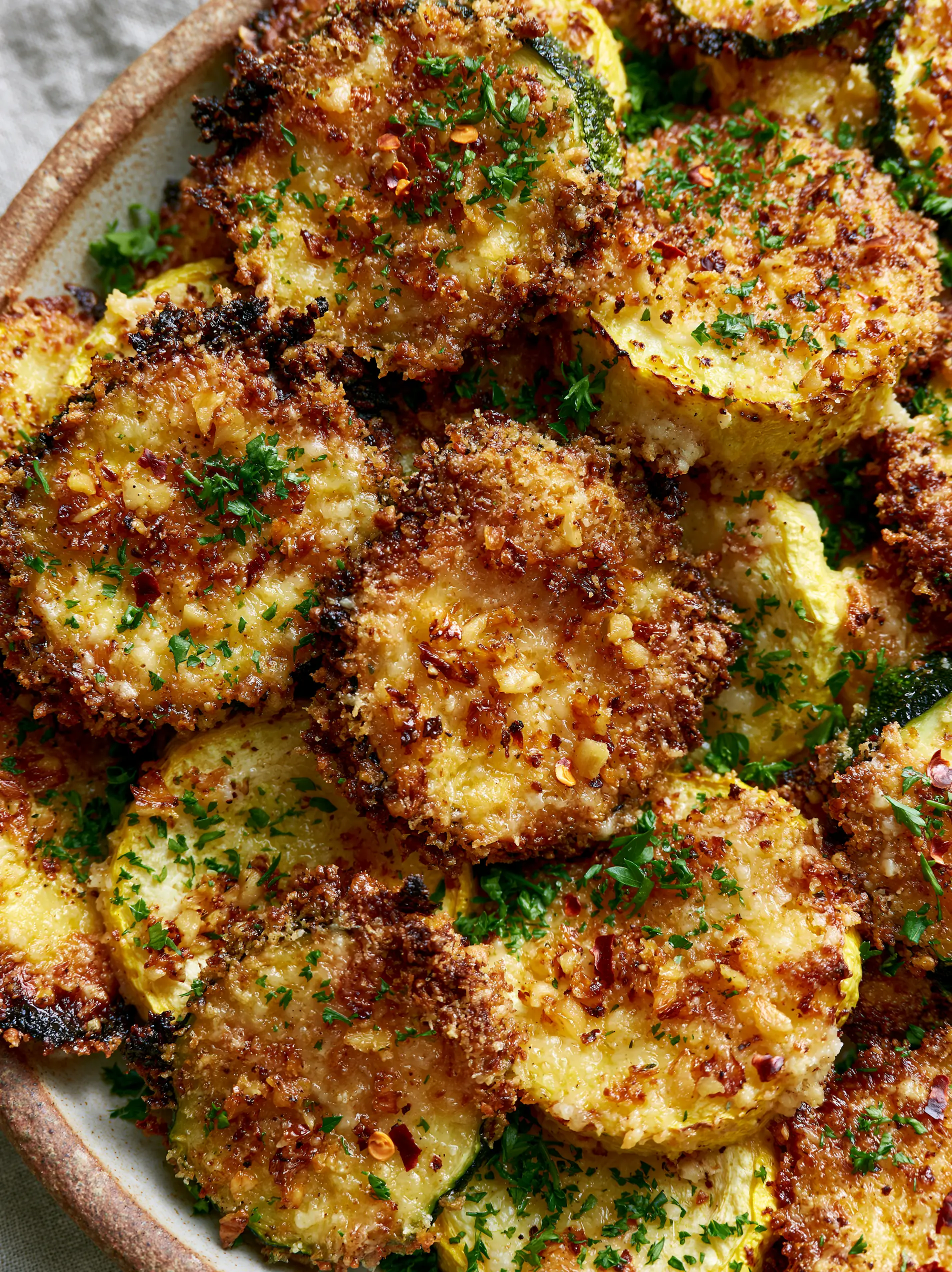 Close-up of roasted green zucchini and yellow squash rounds with a thick parmesan crust and charred edges. (garlic parmesan zucchini and squash medley)