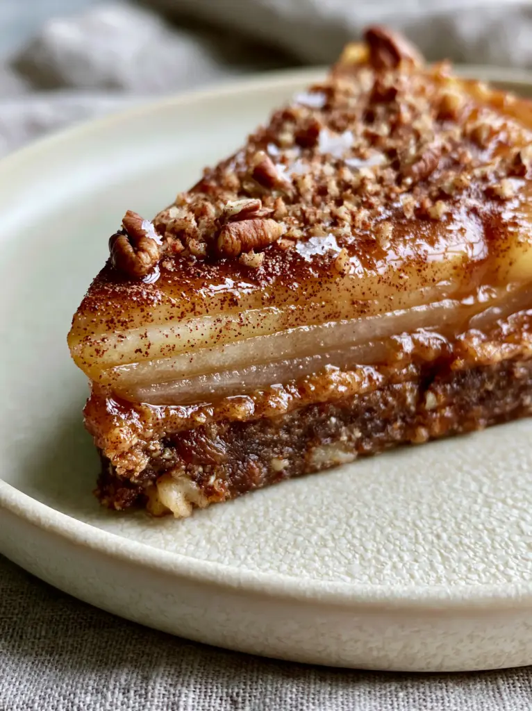A slice of Raw vegan apple pie showing the thick compressed walnut crust and vertical apple arrangement.