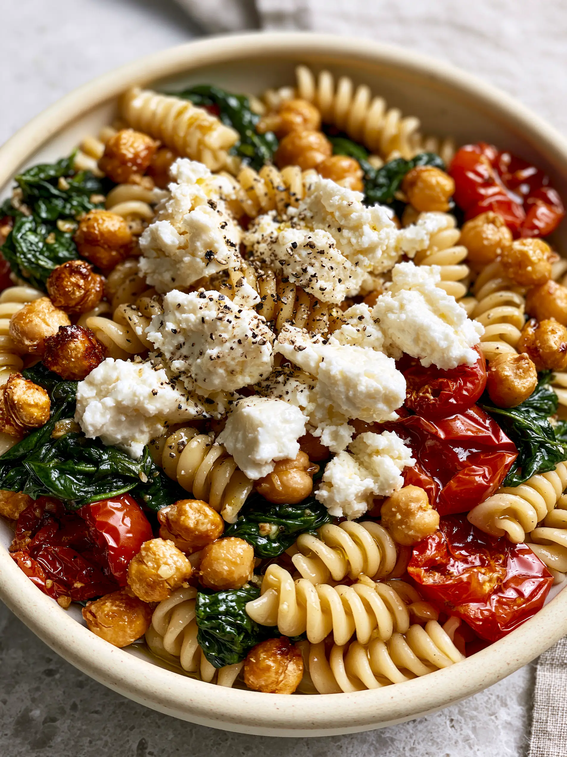 Close-up of glossy garlic fusilli with emerald spinach and bursting cherry tomatoes. (vegetarische rezepte)
