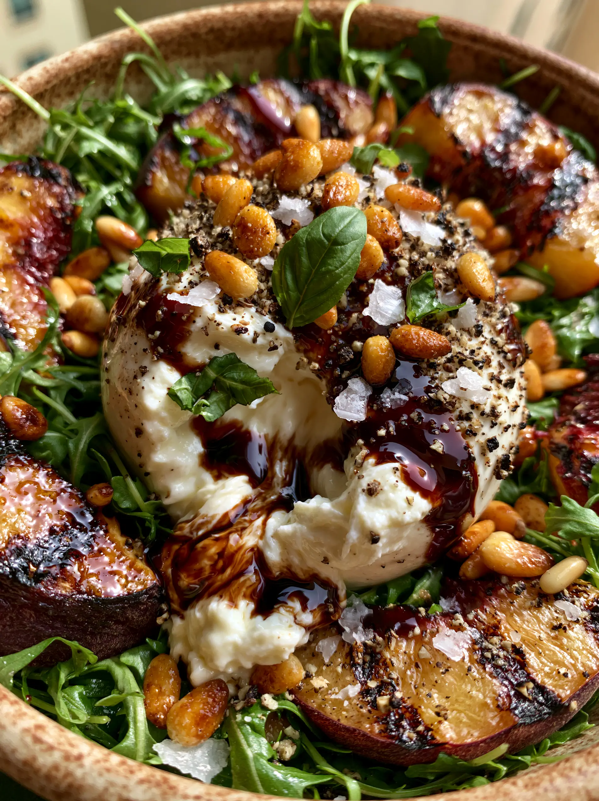 Macro photography of torn burrata cheese showing the creamy stracciatella center in a peach salad recipe.
