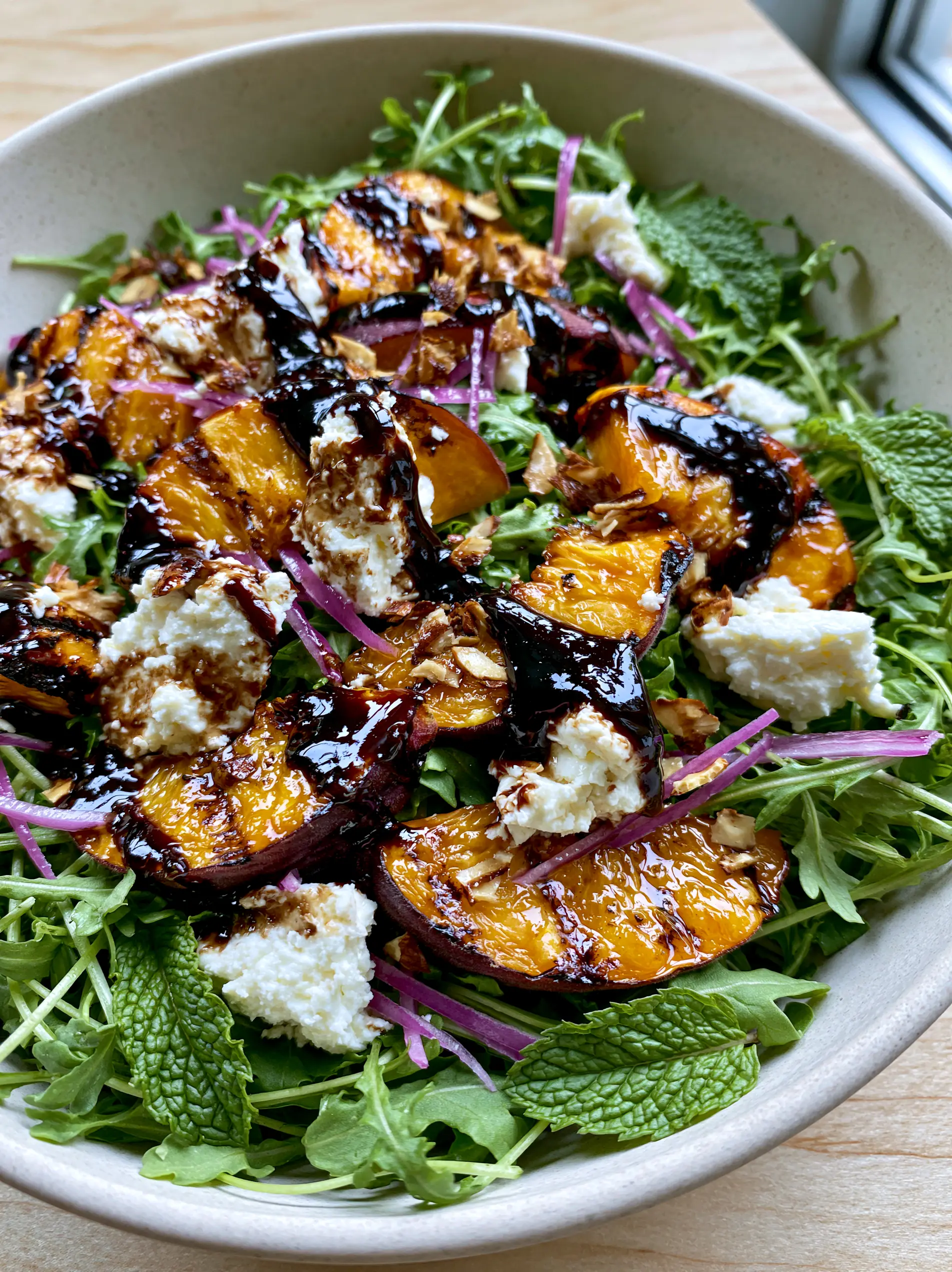 Top-down view of peach feta salad featuring charred peach wedges and glossy balsamic drizzle. (peach feta salad)