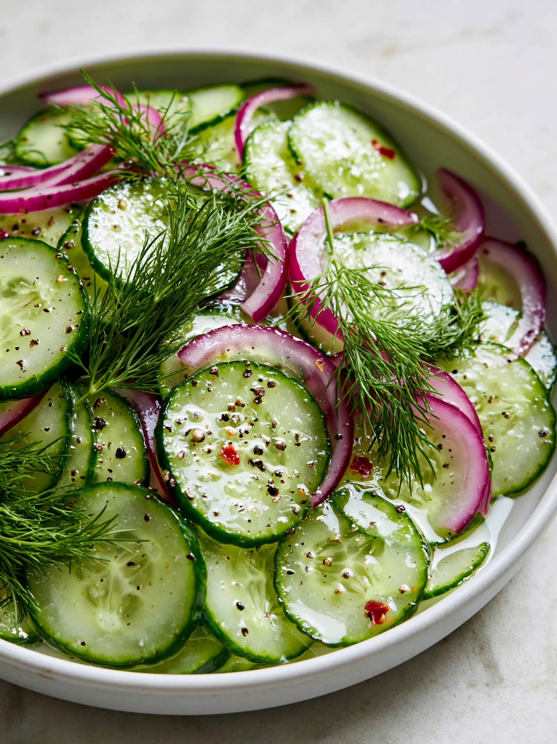 Close-up of vinegar cucumber salad showing the glistening clear dressing and hyper-sharp edges of the emerald cucumber skins.